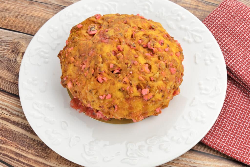 Brioche Pralines Roses – Gourmandise Française Unique Brioche aux pralines roses sur assiette blanche décorée, posée sur une table en bois avec une serviette rouge.